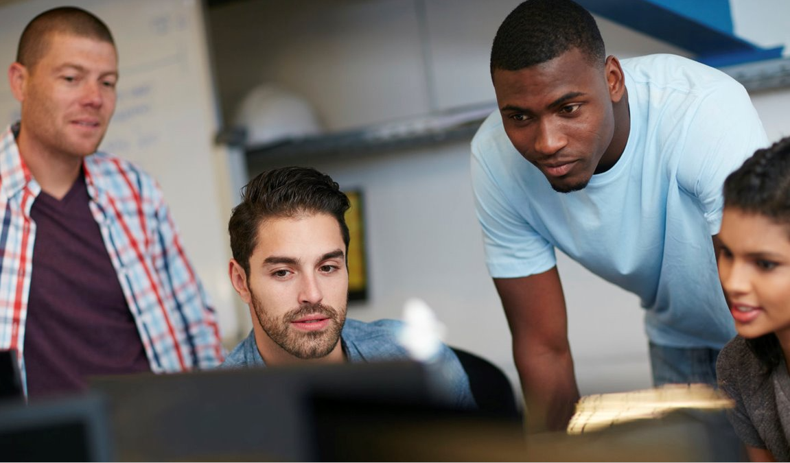 Four students working together and looking at computer screens